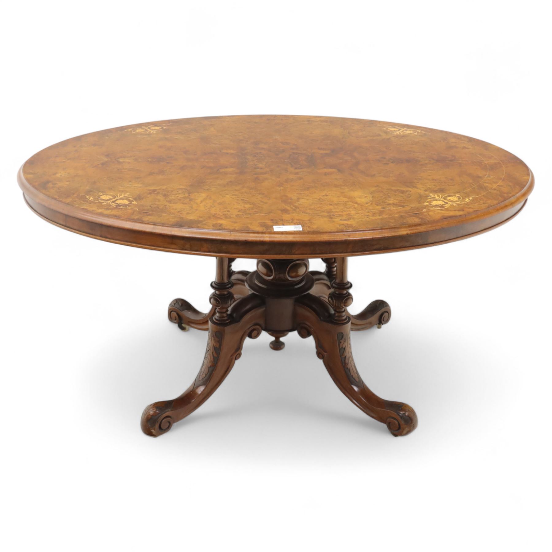 Victorian inlaid burr-walnut and marquetry oval centre table, quarter veneered tilt-top with scrolling foliate and floral marquetry reserves on a turned carved column with clustered supports raised on four out-swept scroll legs on ceramic castors  
