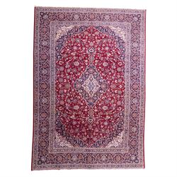 Central Persian Kashan hand-knotted carpet, madder red field with central cusped medallion...