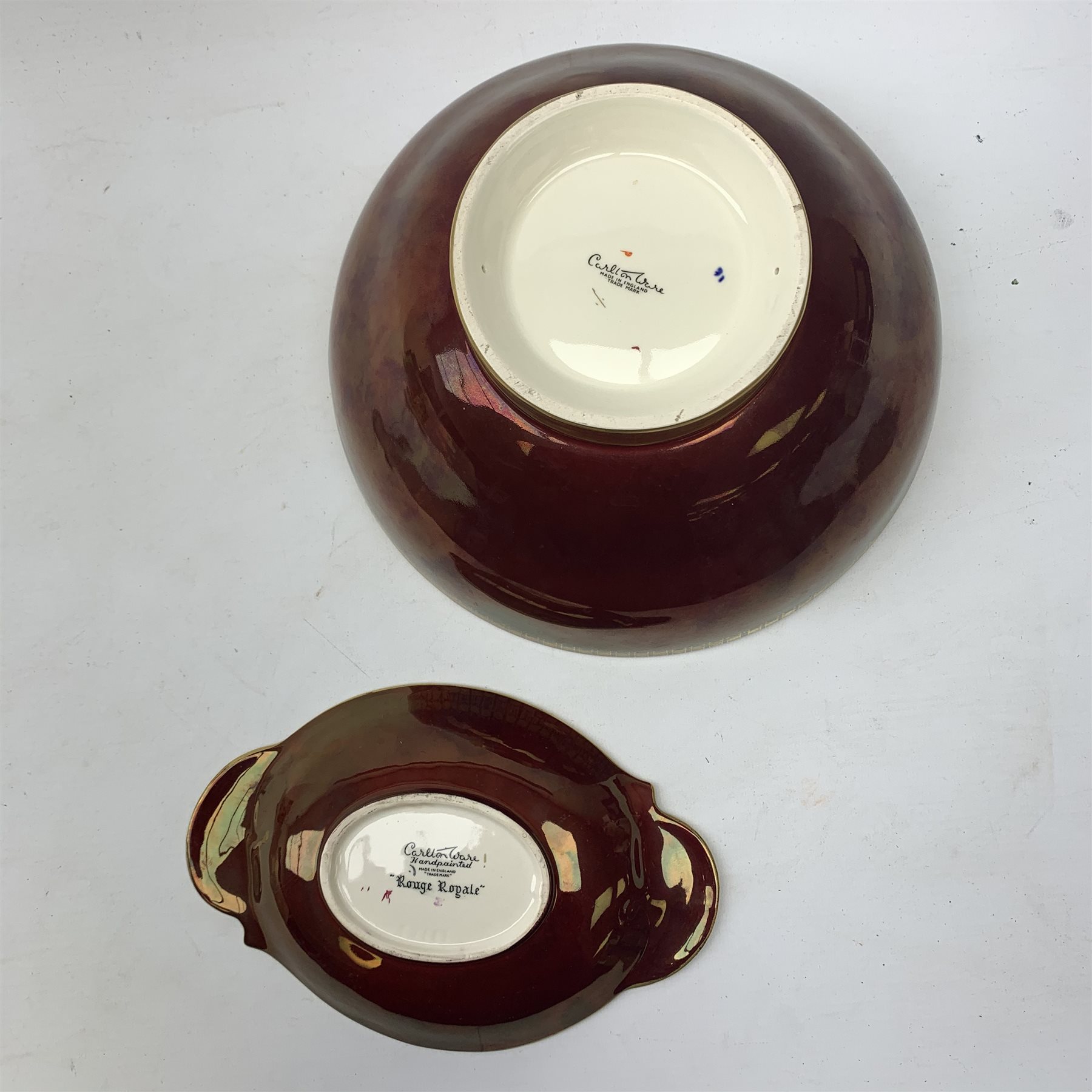 A large Carlton Ware Rouge Royale bowl, the interior decorated with dragonflies, lilies and bulrushes in enamel and gilt, with marks beneath, D25.5cm, together with a Carlton Ware Rouge Royal dish, decorated with grape vines, with marks beneath, L21.5cm. 