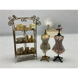 Collection of miniature dolls house ladies furniture and accessories, to include three piece green dressing table set decorated with lace and gilt, flowers, scent bottles, etc, upholstrered cream counter with makeup,  jewellery stand, gloves etc, ornate three tier shelving unit with various bottles, mannequins, hat boxes etc