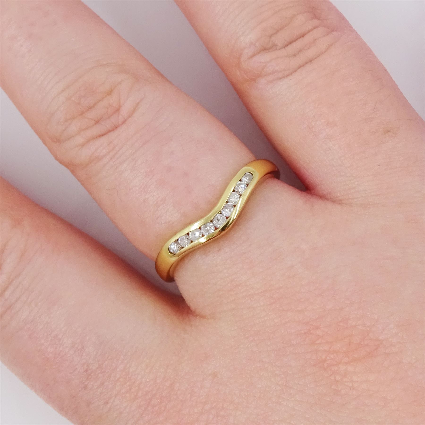18ct gold diamond wishbone ring, channel set with nine round brilliant cut diamonds, Birmingham 1994, total diamond weight 0.15 carat