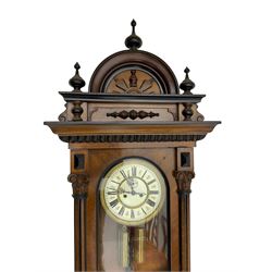 German - late 19th century mahogany 8-day Vienna regulator, with an arched pediment with turned finials, fully glazed door flanked by reeded pilasters with carved capitals, ogee base with conforming turned pendants, two part enamel dial with Roman numerals, minute track and seconds dial, weight driven movement striking the hours and half hour on a coiled gong.  With weights and pendulum.