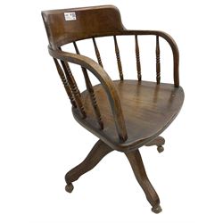 Early 20th century oak framed swivel Captain's chair, tub shaped back with turned spindle supports over saddle shaped seat, quadriform base on castors