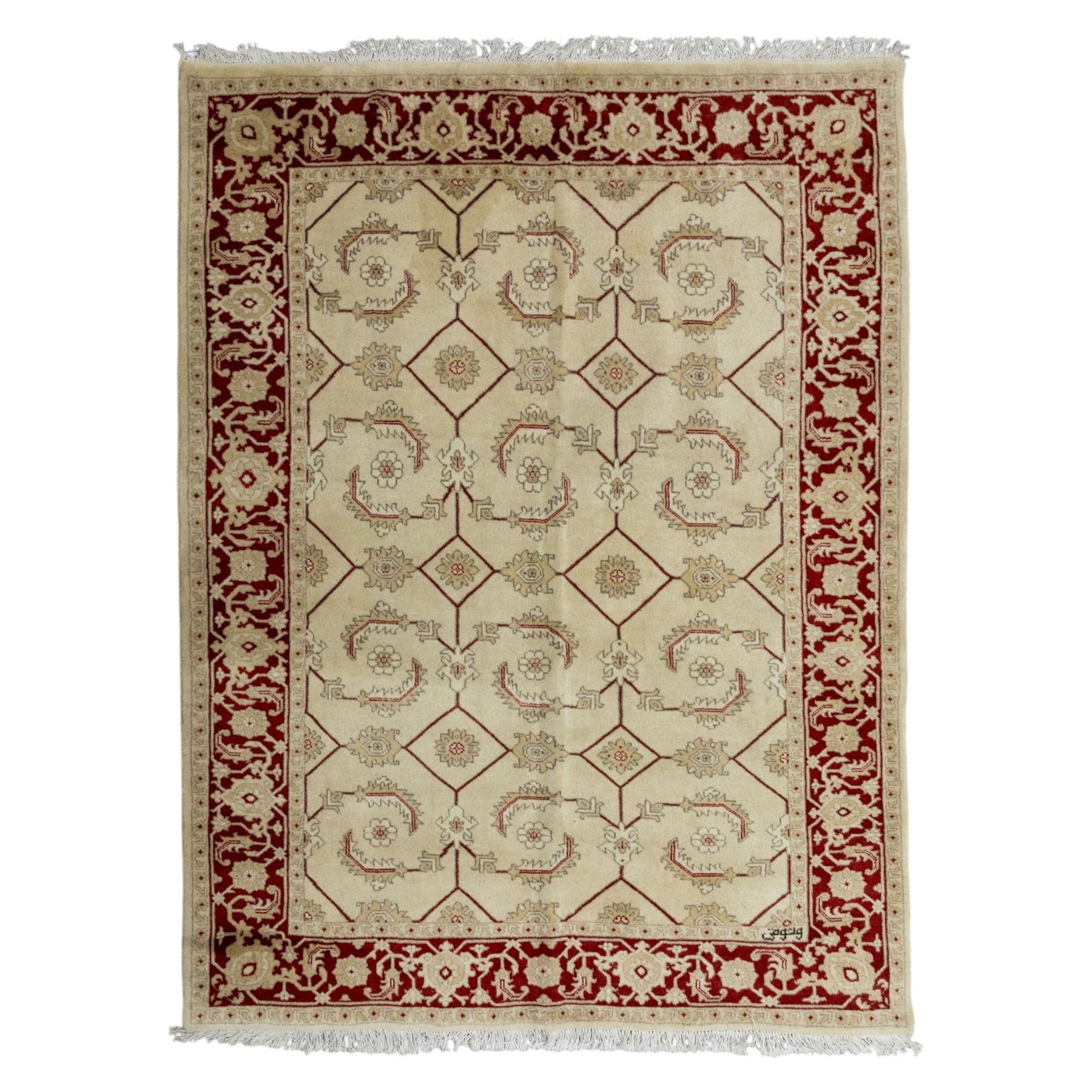 Baluchi signed hand-knotted rug, ivory ground, with an all-over geometric lattice design incorporating stylised flowerheads, hooked motifs and angular vine work, enclosed by a crimson border with repeating floral motifs and scrolling vines, flanked by narrow patterned guard stripes, signed to one corner, with cotton fringes