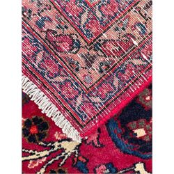 North East Persian Meshed fuschia ground carpet, the floral pole medallion flanked by banners with palmette motifs, surrounded by scrolling and interlaced branches of foliage, the border with bands of Boteh motifs, decorated with repeating stylised plant and flower head designs