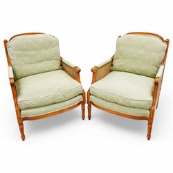 French Empire design varnished wood three piece lounge suite comprising of two cane armchairs and matching sofa, carved top rails with foliate terminals, cane side panels and padded scroll arms, upholstered in a green brocade with matching piping, on fluted legs