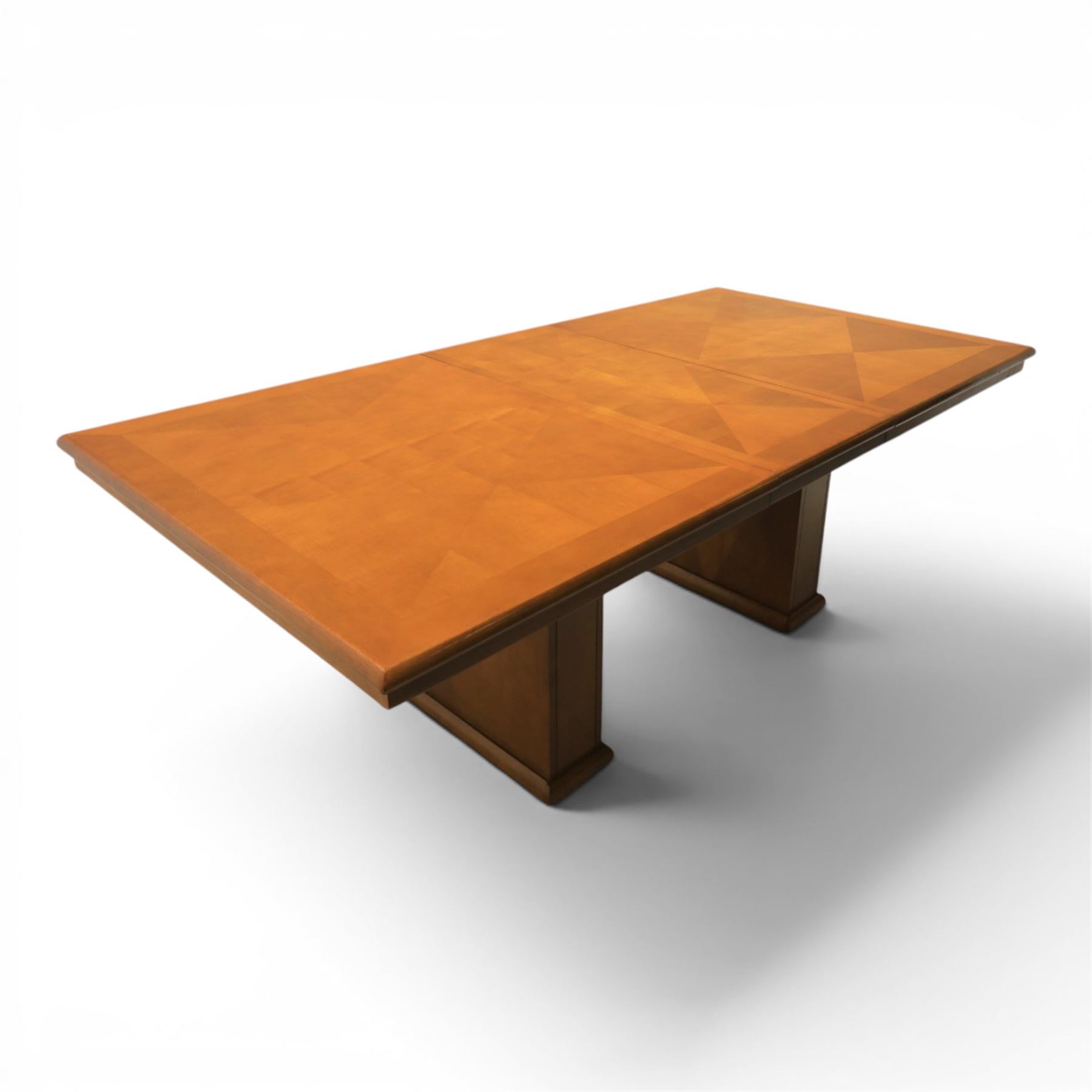 Modern Art Deco design walnut extending dining table, rectangular top with rounded moulded edge, geometric parquetry veneered panels, extending action with additional leaf extending to 220cm, on twin panelled pedestal supports with stepped plinth feet