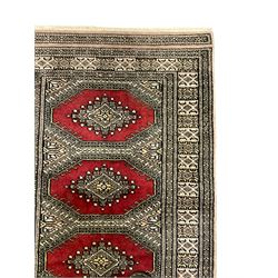 Persian peach and red ground rug, the field decorated with canted rectangular panels, repeating stylised floral design border (94cm x 63cm); and a similar rug signed by the weaver (90cm x 63cm)