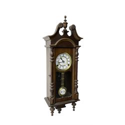 Continental - 31day spring driven wall clock in a mahogany case, with a swan neck pediment with a central finial and paterie, glazed door with turned half-columns and pendants, two part dial with Roman numerals, spade hands, and visible grid iron pendulum, movement striking the hours and half hours on a coiled gong.