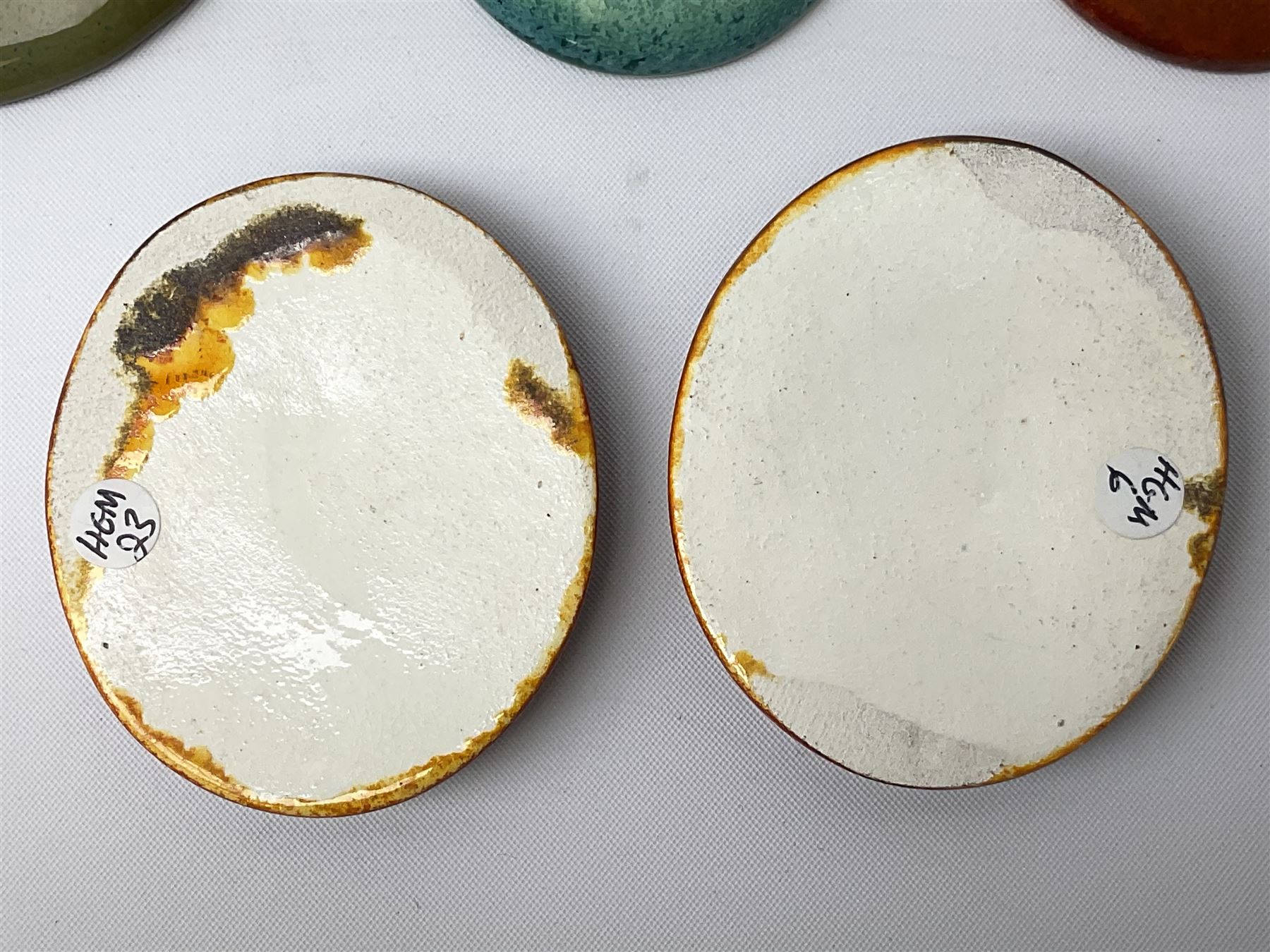 Henry George Murphy (1884-1939), collection of seven Arts & Crafts glazed ceramic roundels, of circular and oval form, five in tones of red and brown and two in tones of blue, turquoise and green in soufflé and high fired finishes, largest example D6.5cm