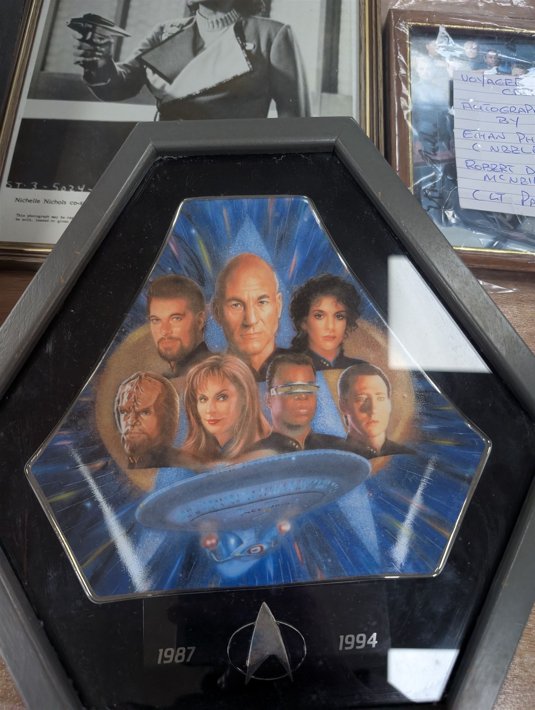 Collection of Star Trek The Next Generation and Deep Space Nine memorabilia, including two limited edition signed Star Trek Deep Space Nine photographs, commemorative porcelain plaque, insignias, Encounter at Farpoint pewter plaque, signed photograph of the Voyager crew, two signed copies of Convergence and a signed War & Madness graphic novel, canvas prints and other signed photos, together with Star Wars Ray Park (Darth Maul) signed photograph, UFO and Buck Rogers memorabilia