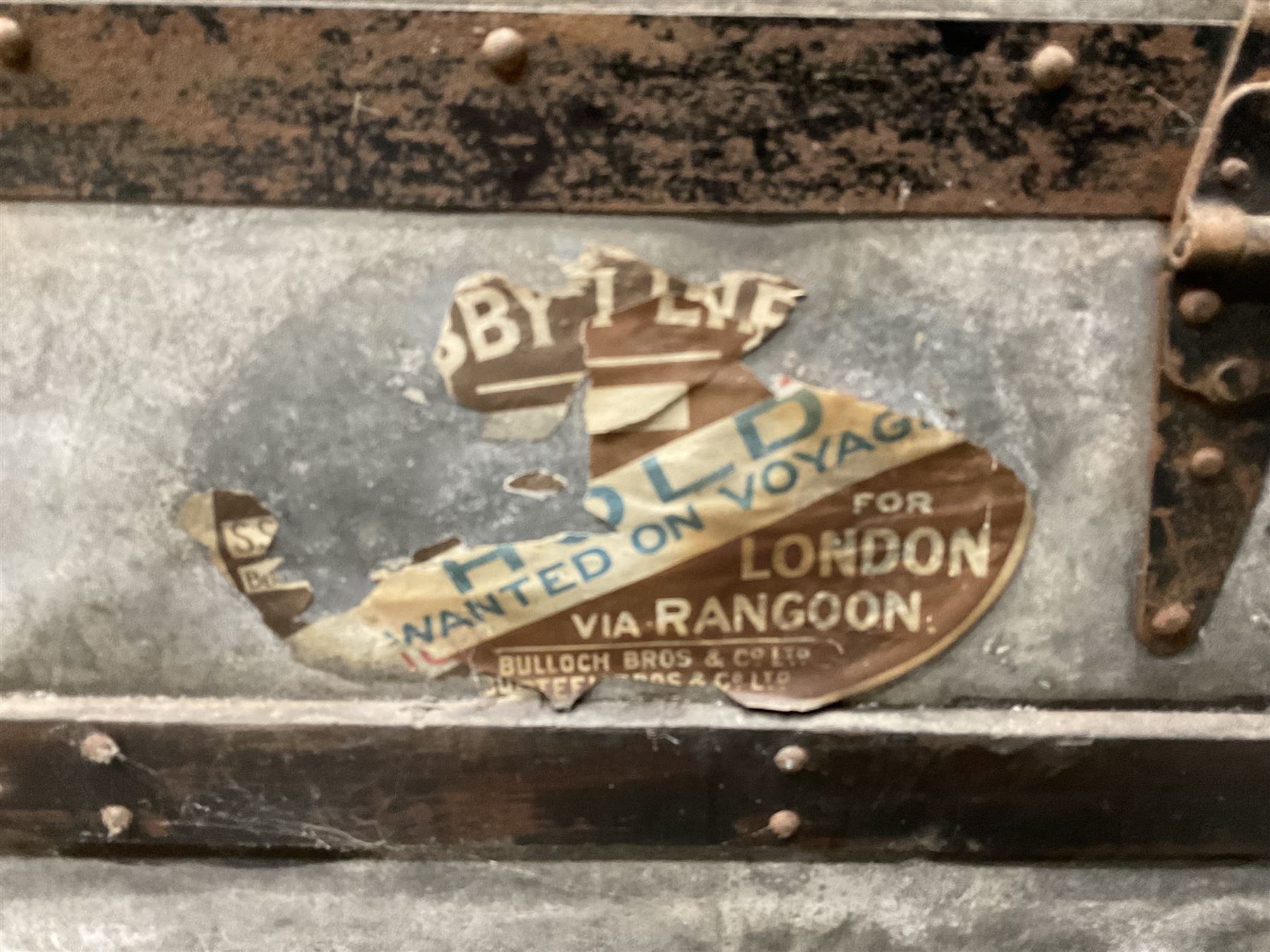 Early 20th century wood and metal bound zinc travelling trunk, hinged top with three clasps, decorated with period luggage labels