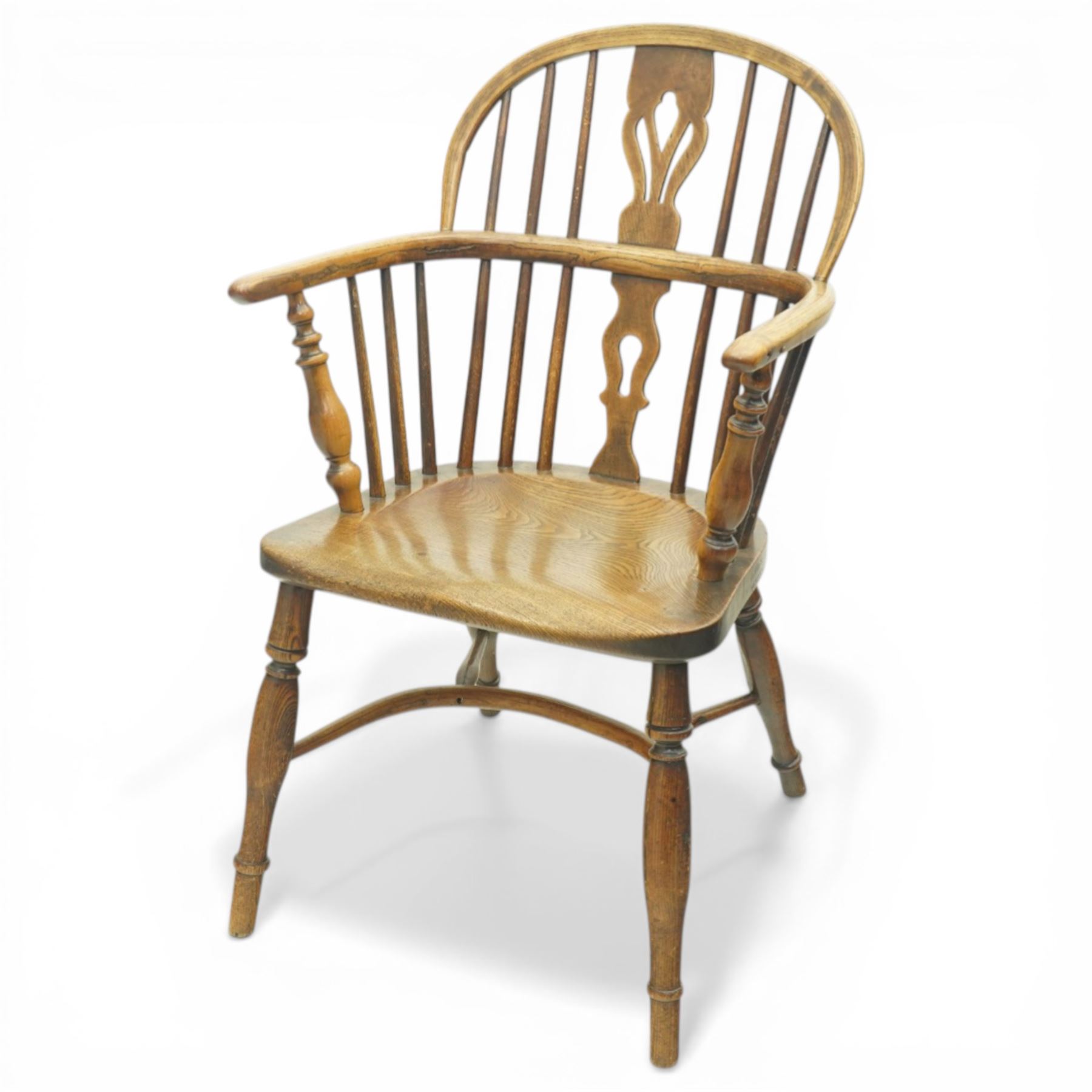 19th century low back elm Windsor armchair, hooped back with pierced central splat and radiating spindles, shaped arm bow over saddle seat, on turned supports united by crinoline stretcher