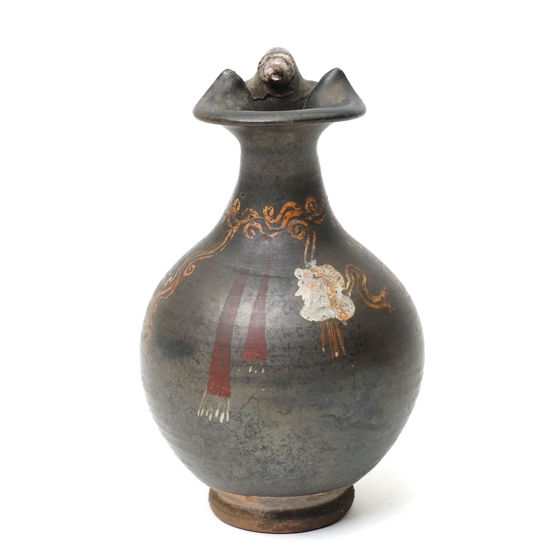 South Italian Gnathian terracotta oinochoe (jug) Apulian or Campanian (Late 4th century BC c.325-300 BC) of elegant ovoid form with trefoil mouth and single strap handle, the handle terminating in a stylised serpentine motif merging into the pouring lip, the vessel covered in a black gloss slip and decorated in added red, white and yellow with a theatrical mask, fillets and scrolling Dionysiac vine motifs, H19cm 
Notes: Gnathian ware takes its name from Egnathia in Apulia and is characterised by a black-gloss ground with added-colour decoration; the theatrical mask, fillets and vine scrolls relate to Dionysiac imagery associated with the symposium and theatre in South Italian Greek culture of the late fourth century BC. A very similar oinochoe is held in the The Metropolitan Museum of Art, object number 76.12.8