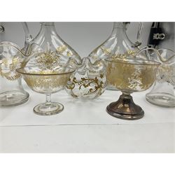 Collection of eleven pieces of French gilded glassware comprising pair of flattened lozenge form decanters with stoppers, pair of cups and saucers, pair of wavy rim vases, two wine glasses, one with replacement hallmarked silver pedestal and frilled rim globular vase (11)