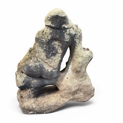 Carved composite stone garden figure, depicting a seated child with folded arms, weathered finish with moss and lichen growth, raised on an integral naturalistic base