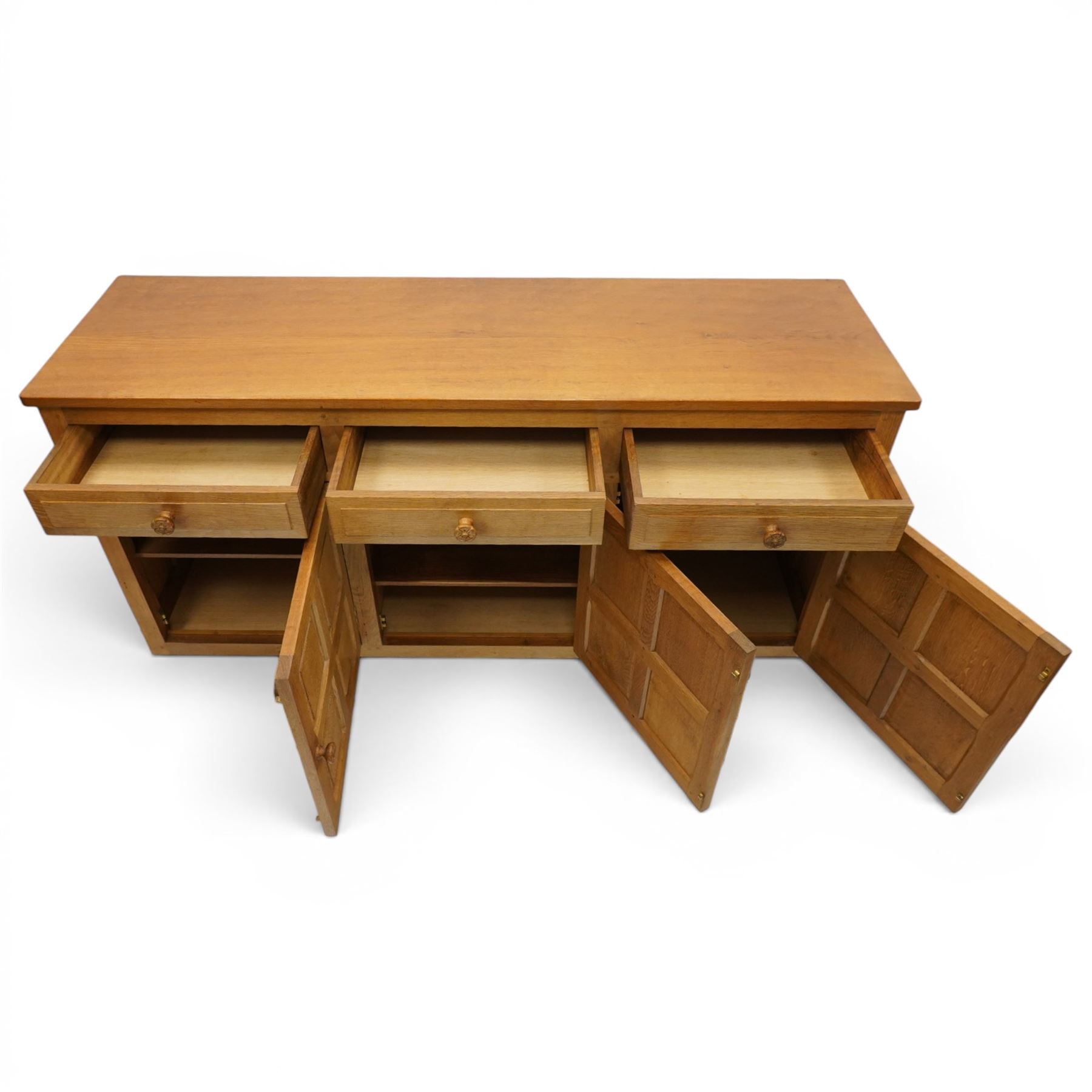 Beaverman - 1980s adzed oak sideboard raised on a trestle base, three drawers over three cupboards with Yorkshire Rose carved handles, fielded panelled sides and front, with carved Beaver, by Colin Almack of Sutton near Thirsk