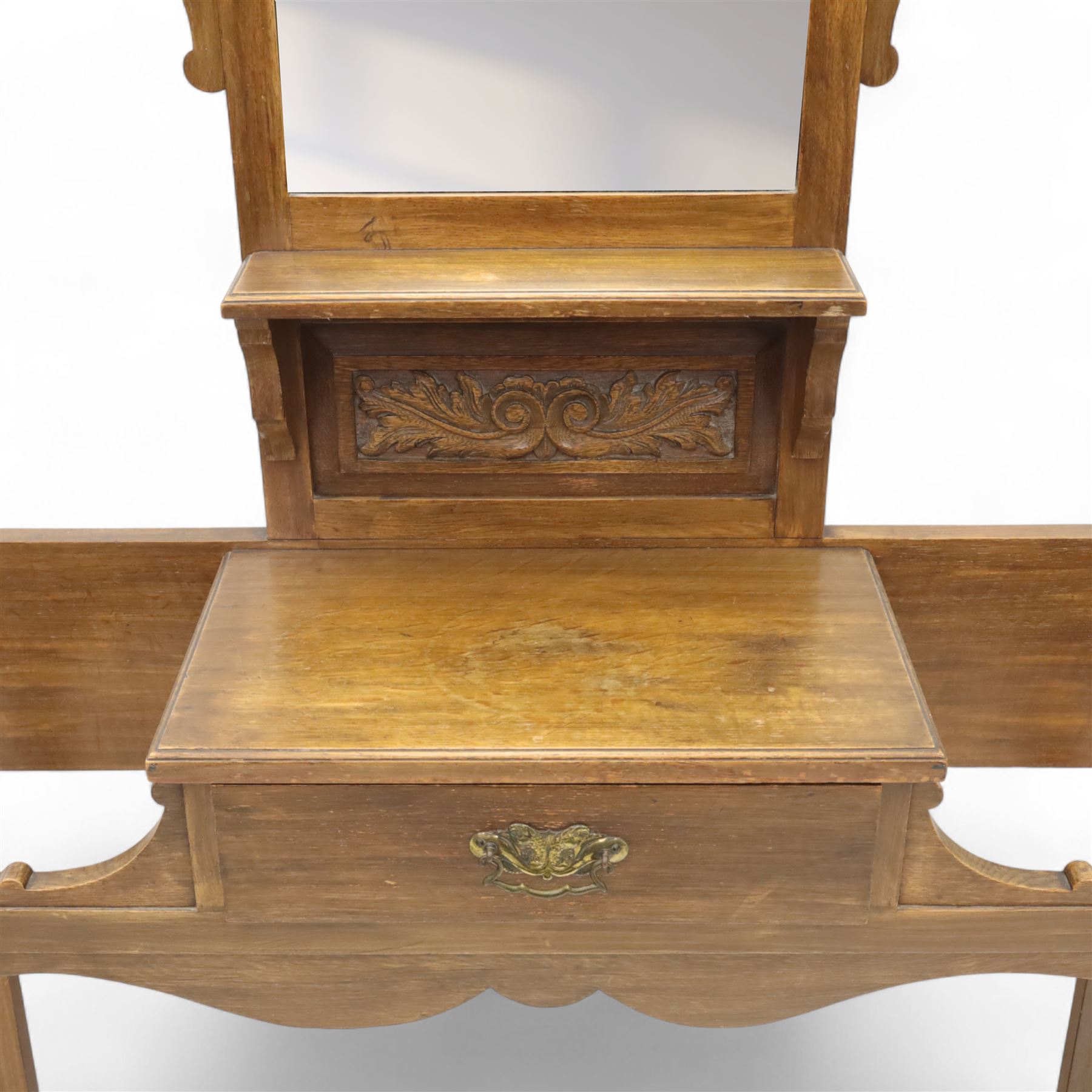 Edwardian walnut hall stand, the shaped pediment above turned spindle gallery and bevelled mirror, fitted with brass double coat hooks, single drawer with cast handle and carved frieze, flanked by turned supports, lower platform fitted with twin metal drip trays