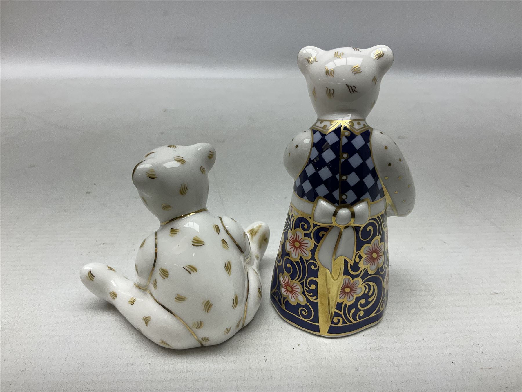 Four Royal Crown Derby teddy paperweights, comprising Teddy Cook, two Teddy George and Seated Teddy, all without stoppers, together with Crown Namestake with gold stopper 