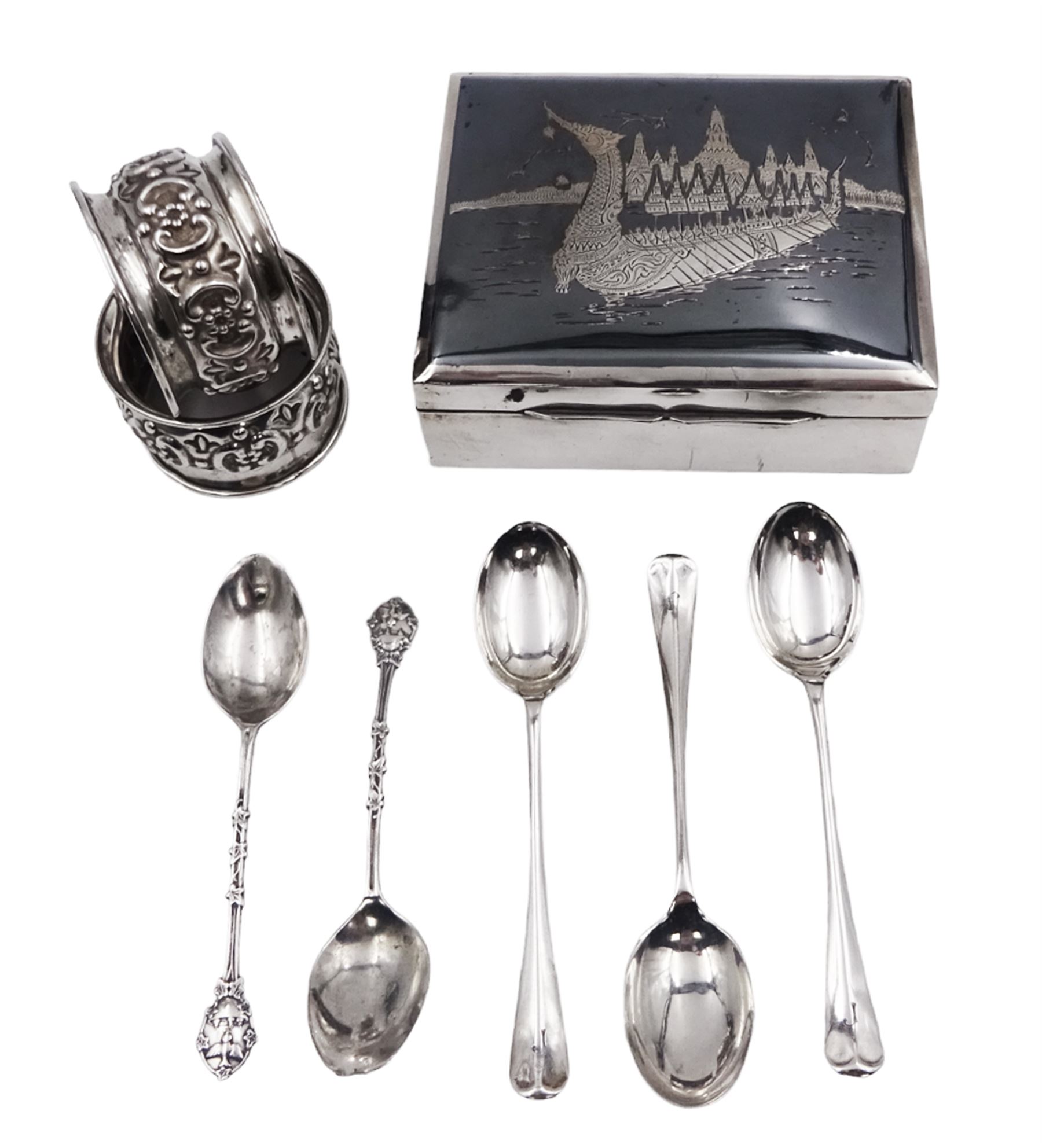 Gorup of silver, comprising pair of Edwardian silver napkin rings, with repousse floral decoration, hallmarked E J Trevitt & Sons, Chester 1903, together with set of three 1930s silver Hanoverian pattern coffee spoons, each with rattail bowls and engraved initial to terminals, hallmarked Frank Cobb & Co Ltd, Sheffield 1936, a pair of early 20th century coffee spoons, each embossed with nesting birds to terminals, with ivy leaf borders and stems, hallmarked Robert James Chaplin & Sons, London 1919, and a Siamese silver mounted cigarette box, with niello work dragon boat scene to cover, lifting to reveal wood lined interior, stamped Sterling Siam, H3.2cm W9.7cm