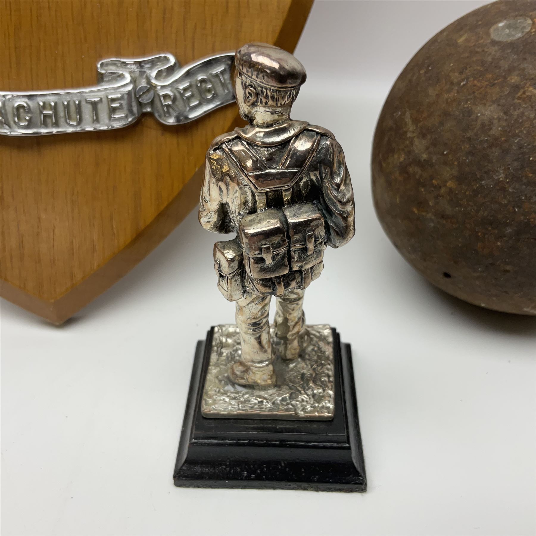 Parachute regiment - chrome crest on oak easel shield; three cloth badges; small silver plated figure; and pin badge; together with 10cm diameter cannon ball etc