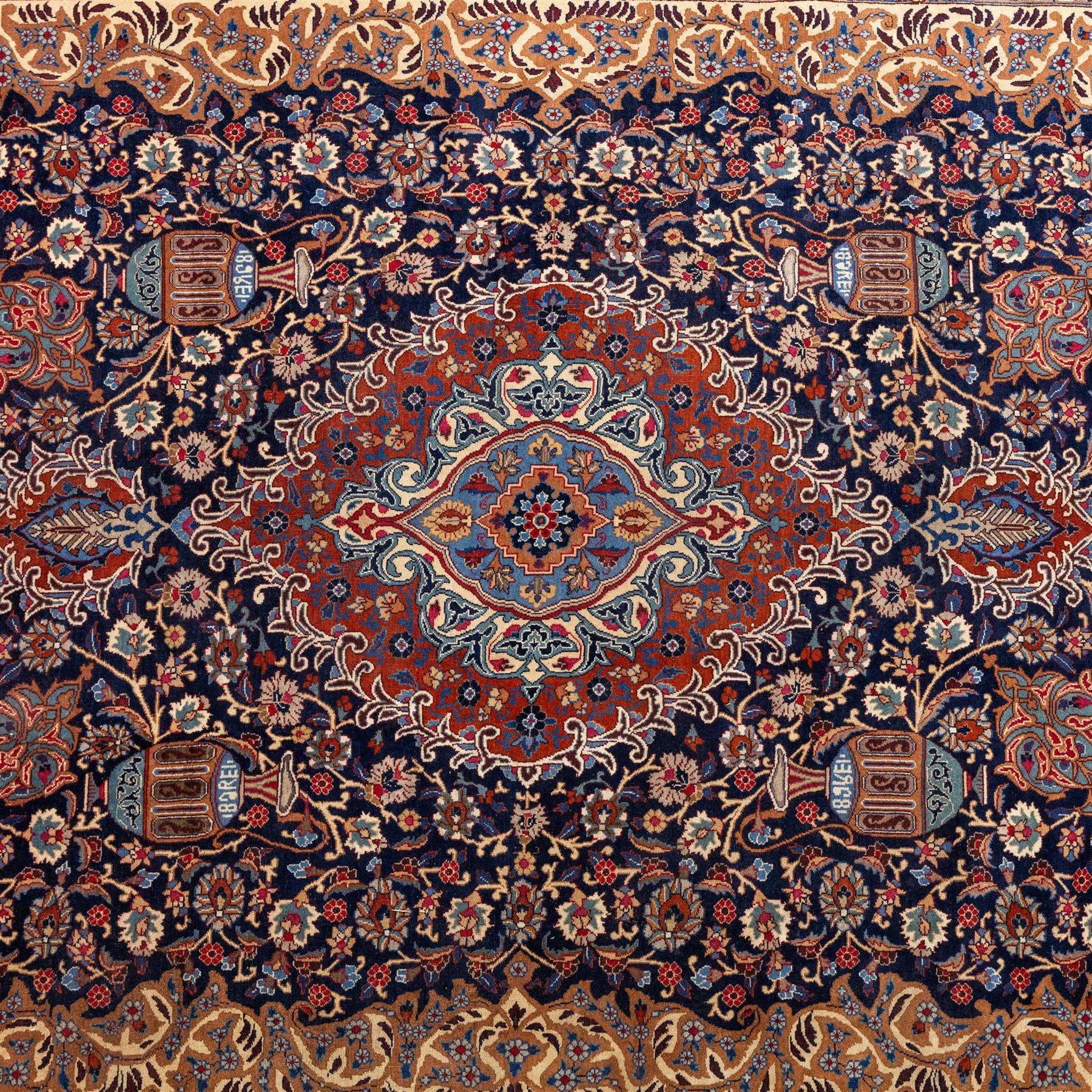 North East Persian Meshed hand-knotted carpet, deep navy field with central complex medallion and densely decorated scrolling floral sprays and palmettes, incorporating cartouche motifs enclosed by a broad tan and dark blue border ornamented by stylized vases flanked by multiple guard stripes, signed 'Amal-e Haji translates as the Work of Haji', with cotton fringe ends 