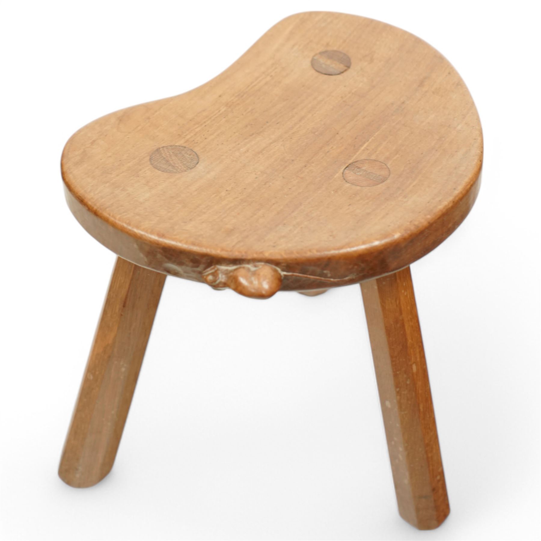 Mouseman - oak three-legged stool, dished kidney-shaped seat on three octagonal splayed supports, carved with mouse signature, by the workshop of Robert Thompson, Kilburn
