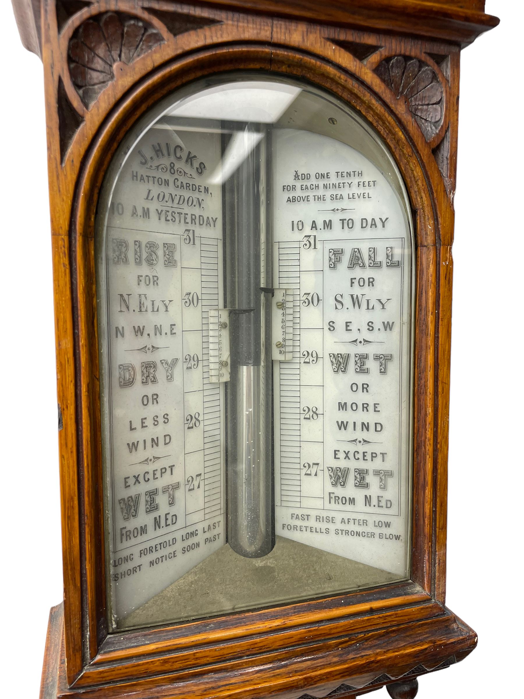 J Hicks - Hatton Garden London, - late 19th century carved oak cased Fitzroy barometer in a richly carved case with a carved crested pediment and square cistern cover, inverted opaline register reflecting FitzRoy's predictions and a scale from 27 to 31 inches of barometric pressure, with a thick bore cistern tube and adjustable rack and pinion twin vernier, fitted with a glazed snail bulb mercury thermometer recording the air temperature in both Fahrenheit and Celsius. Mercury clean and present.
James Joseph Hicks was born in Ireland, however, early in his life he moved to London where he was apprenticed to the instrument maker Louis P Casella. In 1860 he went into business in his own right as a scientific instrument maker at 8 Hatton Gardens. In 1864 he was granted membership to the British Meteorological Society and exhibited instruments at the Royal Society Exhibitions between 1876 and 1913. Hicks was one of London's most prolific and eminent barometer makers. 
