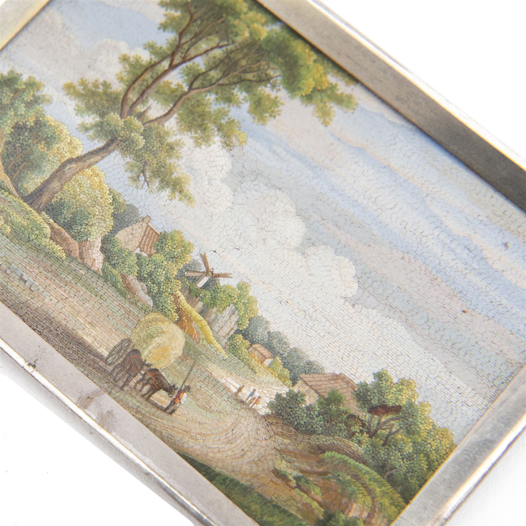 Italian Grand Tour micromosaic plaque, of rectangular form, depicting a rural landscape with figures and horse-drawn cart walking a lane towards dwellings and windmill in the distance, within silver frame, micromosaic 8cm x 5.5cm, including frame 9cm x 6.5cm
