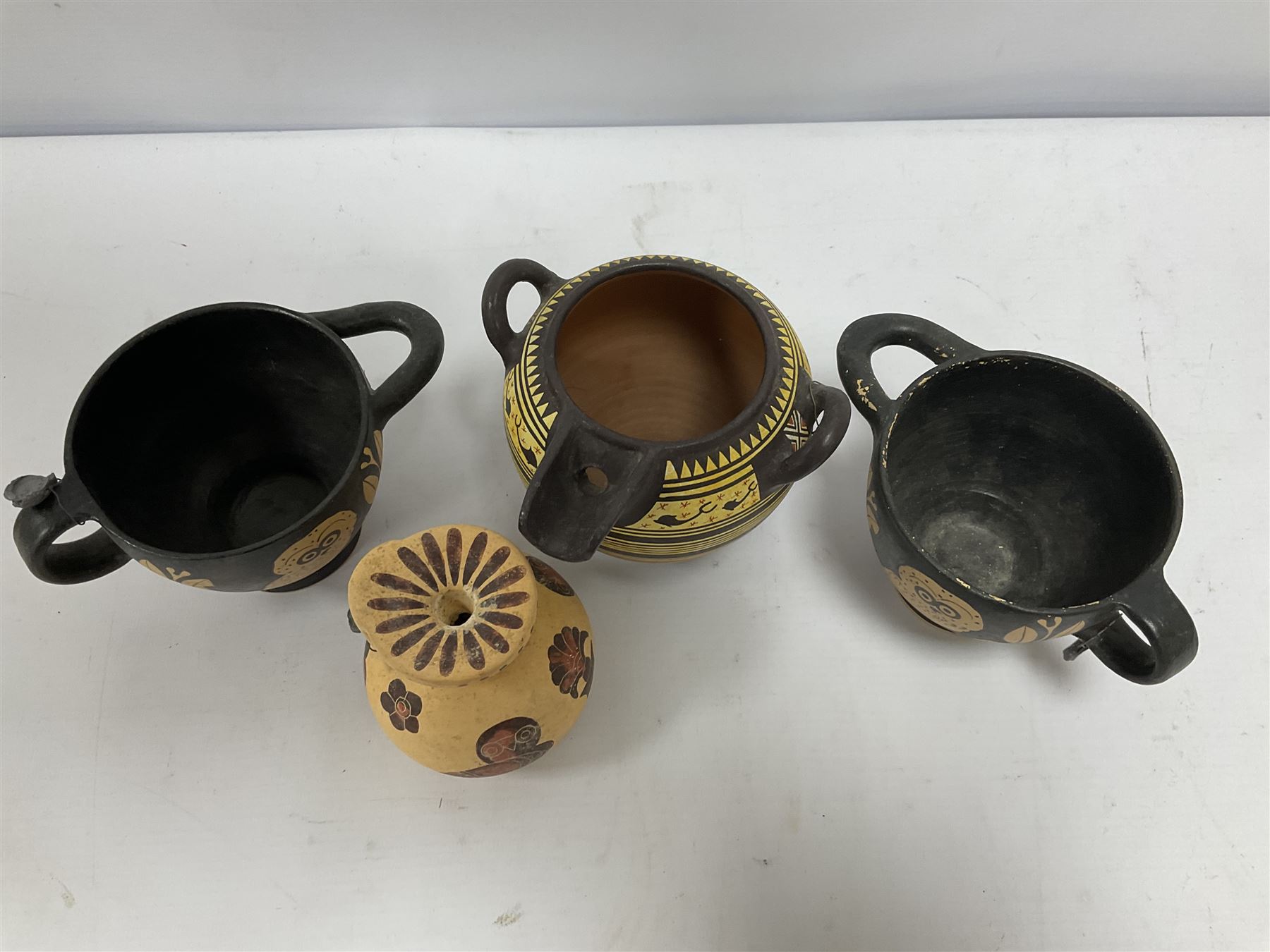 Four examples of reproduction Ancient Greek pottery, to include two skyphoi decorated with the Owl of Athena, standing between two sprays of olive in the manner of 5th century, both signed Attic 500 B.C,  terracotta twin handled vase with spout decorated in the Corinthian Geometric style, in the manner of 6th Century, signed beneath, and a further jug in the 7th Century Corinthian style decorated with flowers and birds