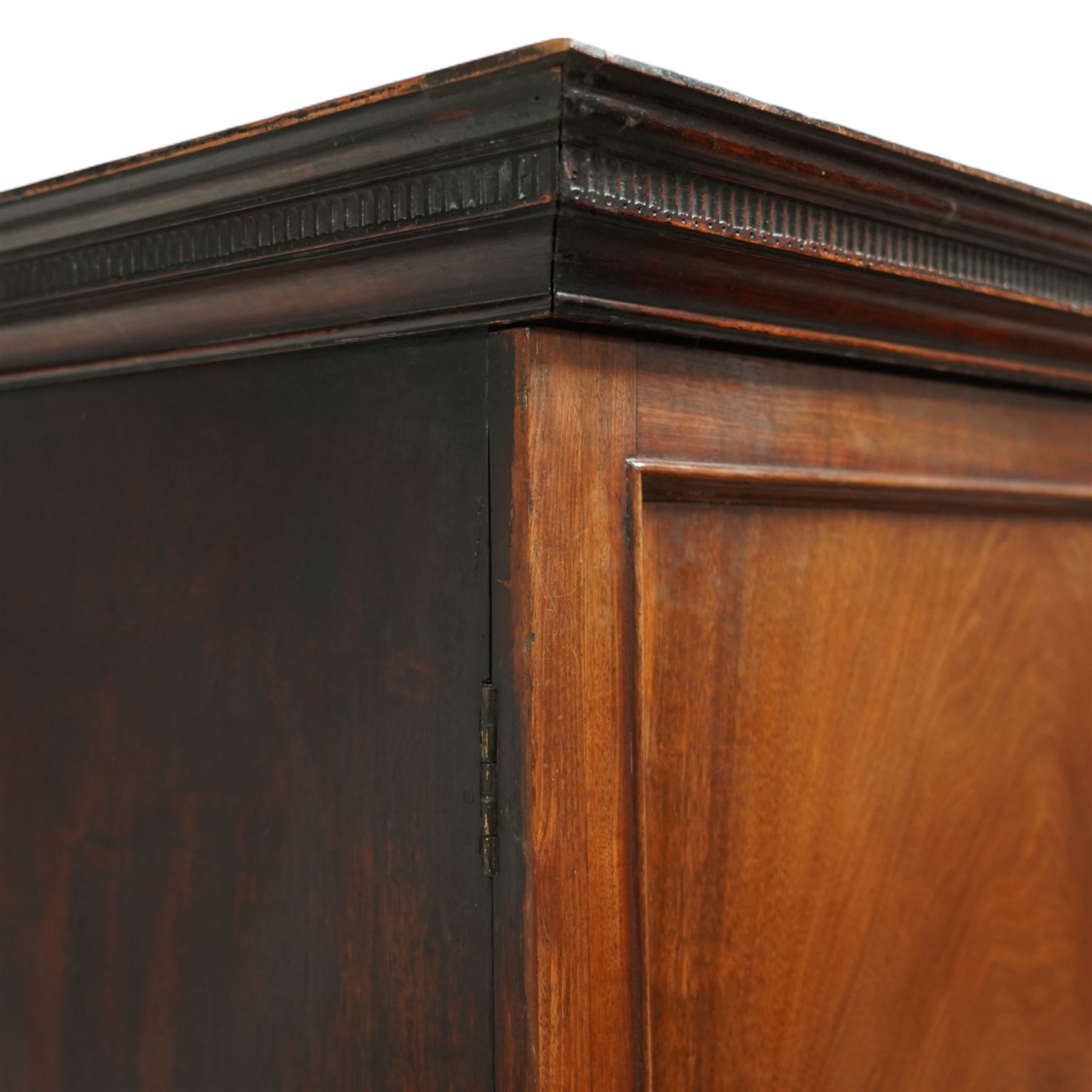 George III mahogany linen press, dentil moulded cornice over a pair of panelled doors enclosing a later fitted interior, lower section with two short over one long cockbeaded drawer, brass swan neck handles, shaped bracket feet