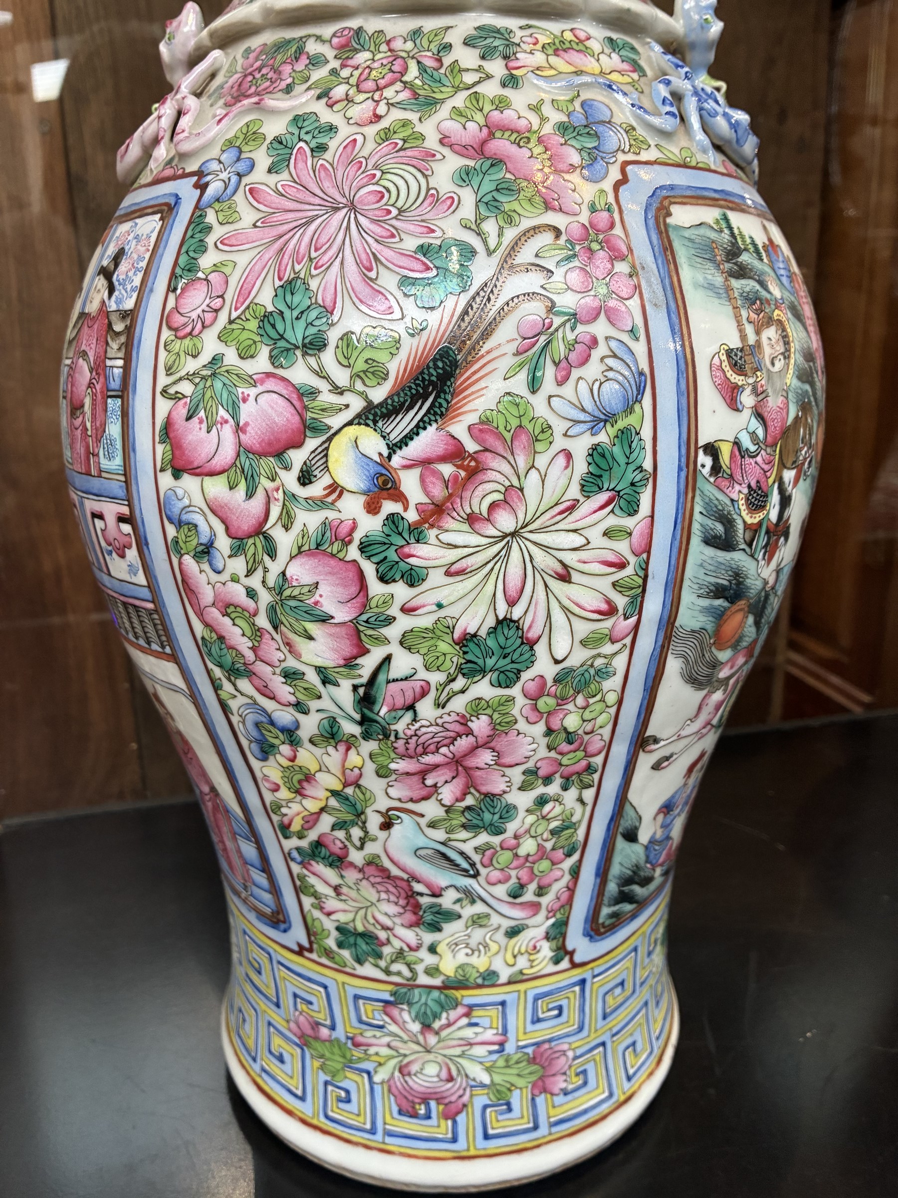 Large pair of 19th century Cantonese famille rose vases, each painted with various courtly scenes, including a display of warriors fighting on horseback before an official and his attendants, double Buddhist lion handles and applied at the shoulders with chilong, the lower band painted with Greek key motif, H58cm (2)