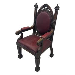 Late Victorian Gothic-revival armchair, arched crest rail carved with tracery and trefoil detail, padded circular back and seat, brass studded burgundy leather upholstery, shaped armrests with scrolled terminals, on square tapering supports