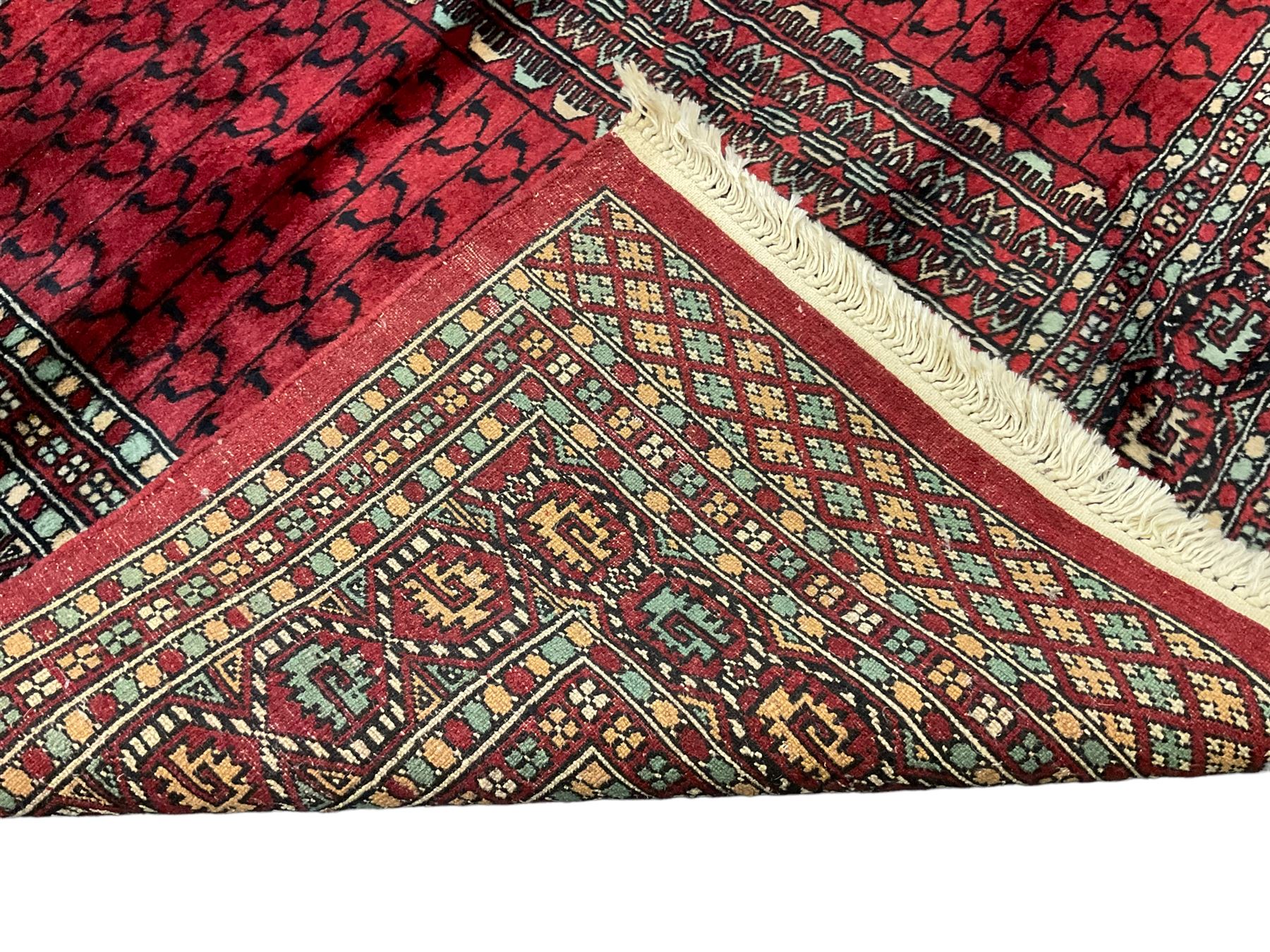 Tekke Ensi crimson ground rug, the quartered field decorated with candelabra motifs, multi-guarded border with repeating geometric hexagonal lozenges in blue and ivory