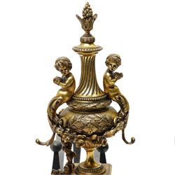 Pair of gilt metal fire dogs, formed as an urn with classical decoration, including putti and floral swags, raised on a square stepped base, the feet formed as rams heads and hoofs, H45cm x W28cm