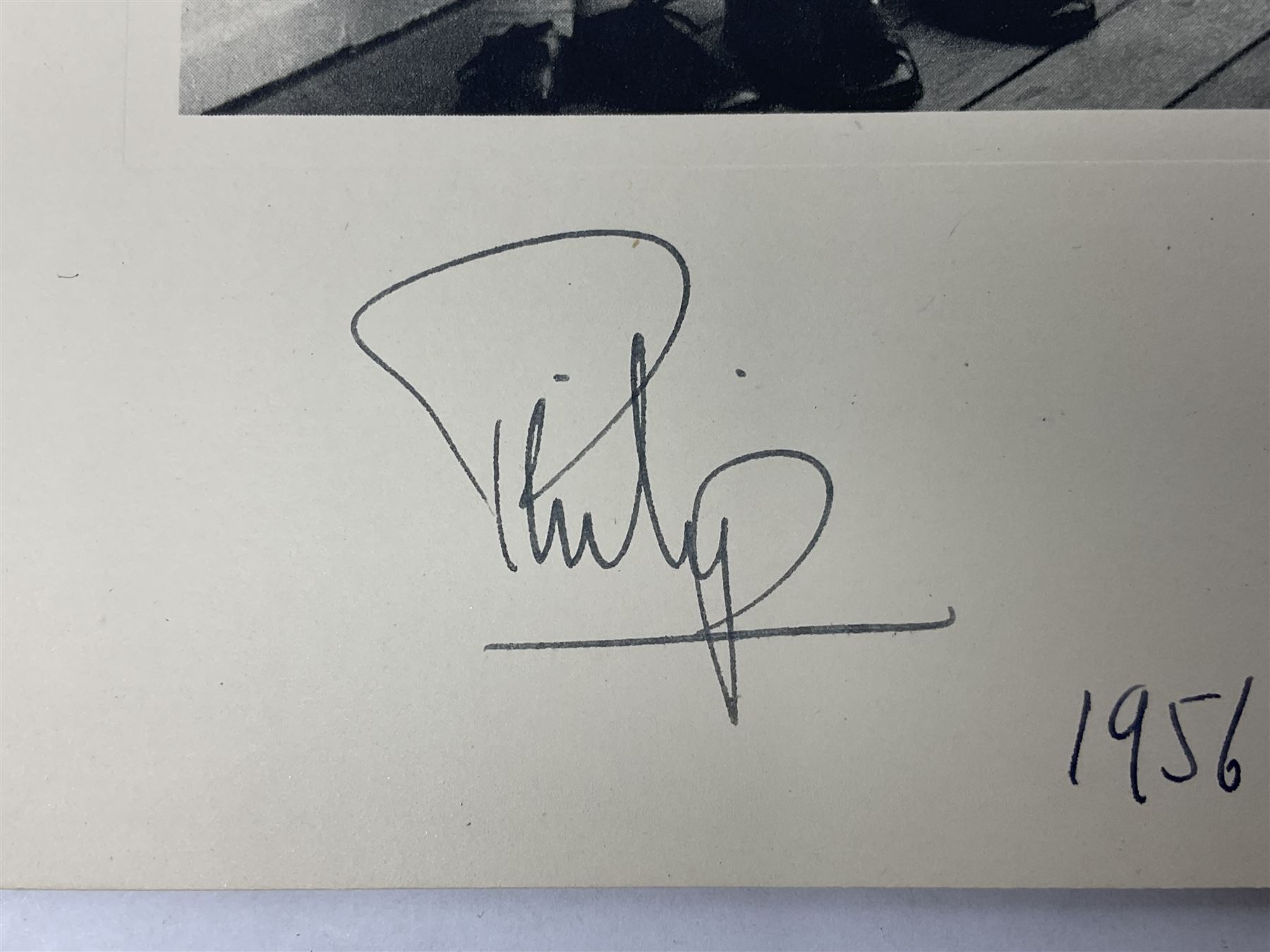 HM Queen Elizabeth II and HRH The Duke of Edinburgh - signed 1956 Christmas card with gilt embossed crown to cover, black and white photograph of the smiling Royal Couple with Prince Charles and Princess Anne on board Britannia, signed in ink 'Philip 1956 Elizabeth R',