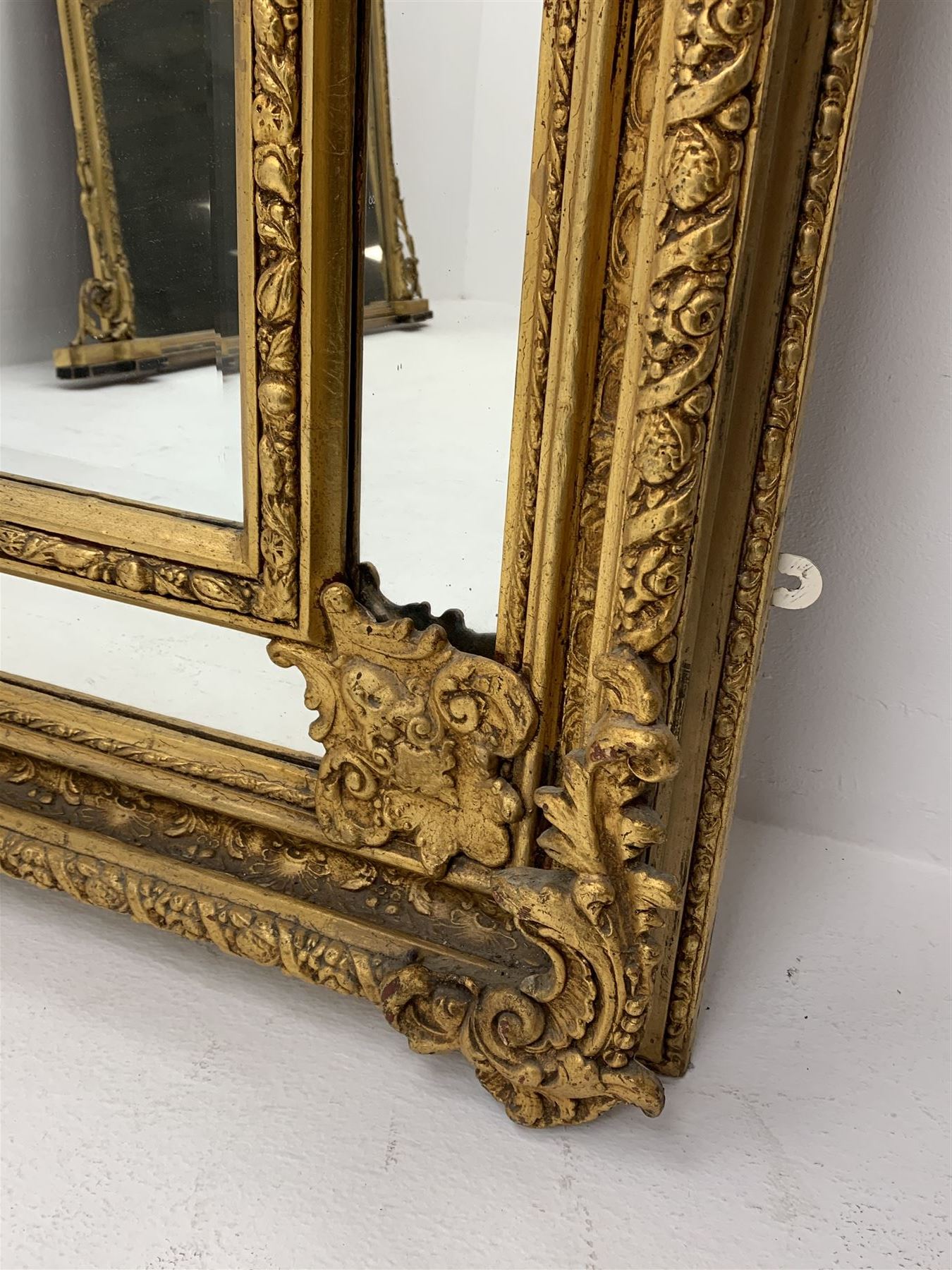 Gilt Rococo style mirror, arched top with central cartouche and oak leaf moulded pediment, floral and fruit moulded surround with segmented glass panels, bevelled central pane, c-scroll shell and acanthus leaf brackets