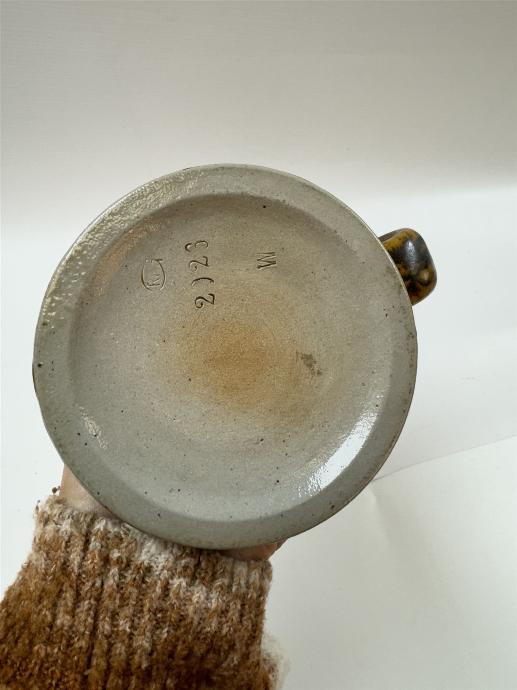 Arts and Crafts or Jugendstil tankard by Richard Riemerschmid, circa 1906, the cylindrical stoneware body reading 'Gaudeamus Igitur' (therefore let us rejoice), and finished in a brown glaze, with engraved slightly domed hinged lid, impressed mark beneath for Reinhold Merkelbach Grenzhausen, model number 2026 W, H14.5cm 