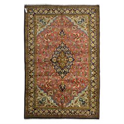 Central Persian Qom hand-knotted carpet, salmon pink ground, with a central dark navy shap...