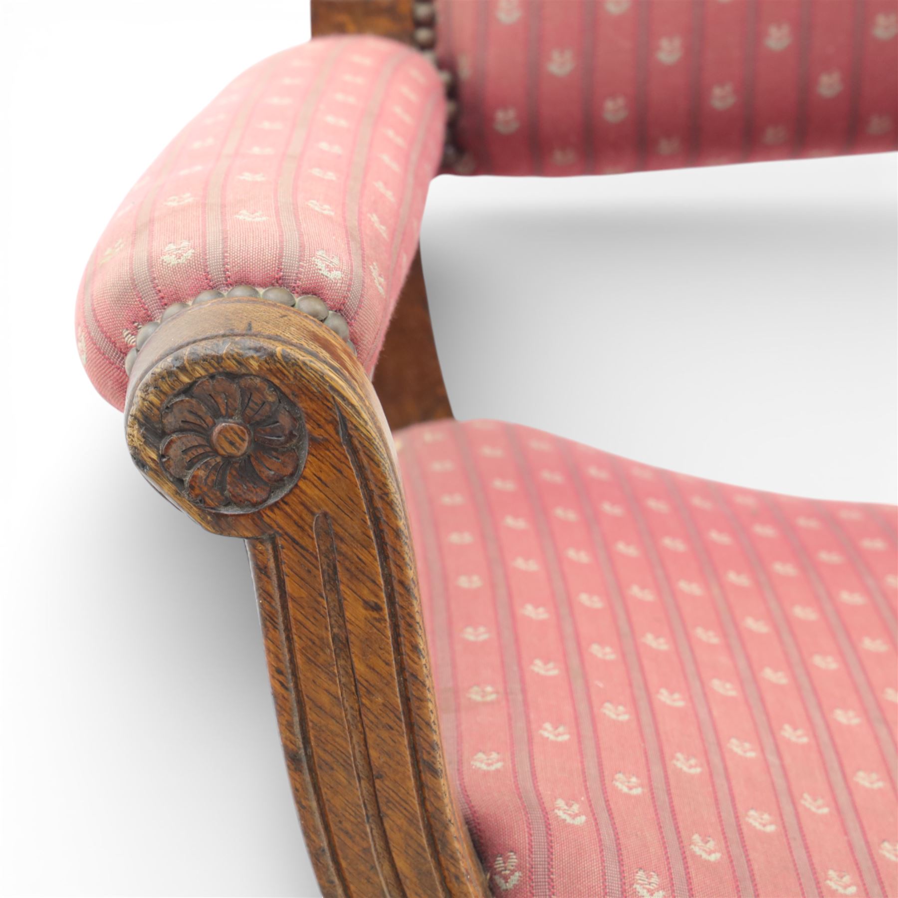 Late Victorian oak x-frame armchair, upholstered padded back and seat covered in pink patterned fabric with close studded borders, shaped downswept arms with scroll terminals, raised on curved x-frame supports with moulded scroll feet