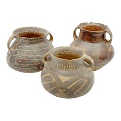 Three Chinese Neolithic pottery vessels, each with twin loop handles to the shoulder and painted geometric banded decoration to the body, all bearing labels for Eskenazi London, tallest H14cm