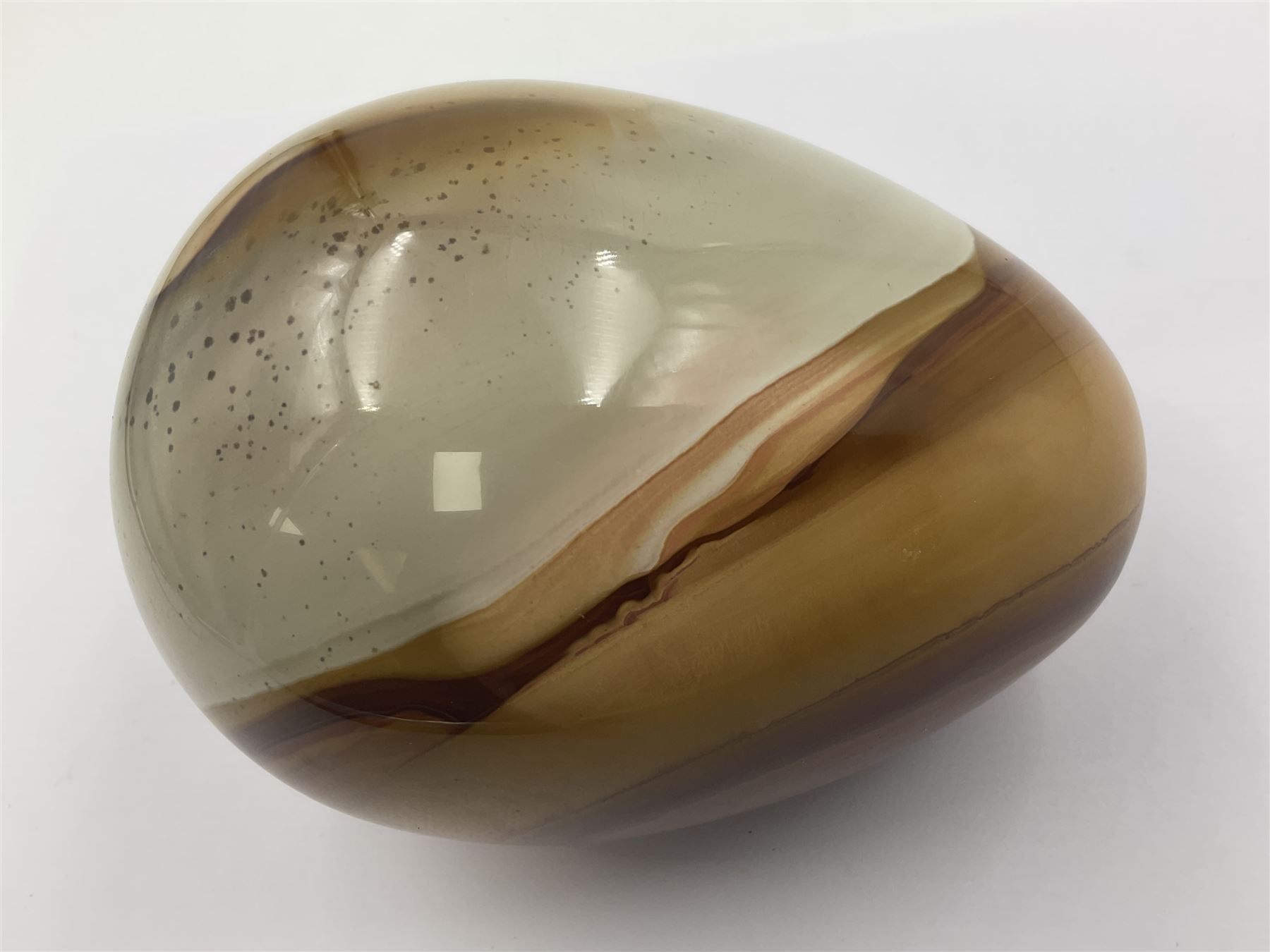 Polychrome jasper specimen egg, in creams, browns and earthy tones, upon a wooden stand, H12cm