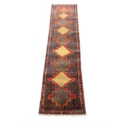 Persian Senneh runner, nine geometric medallions linked on red ground, the field decorated all-over with stylised plant motifs