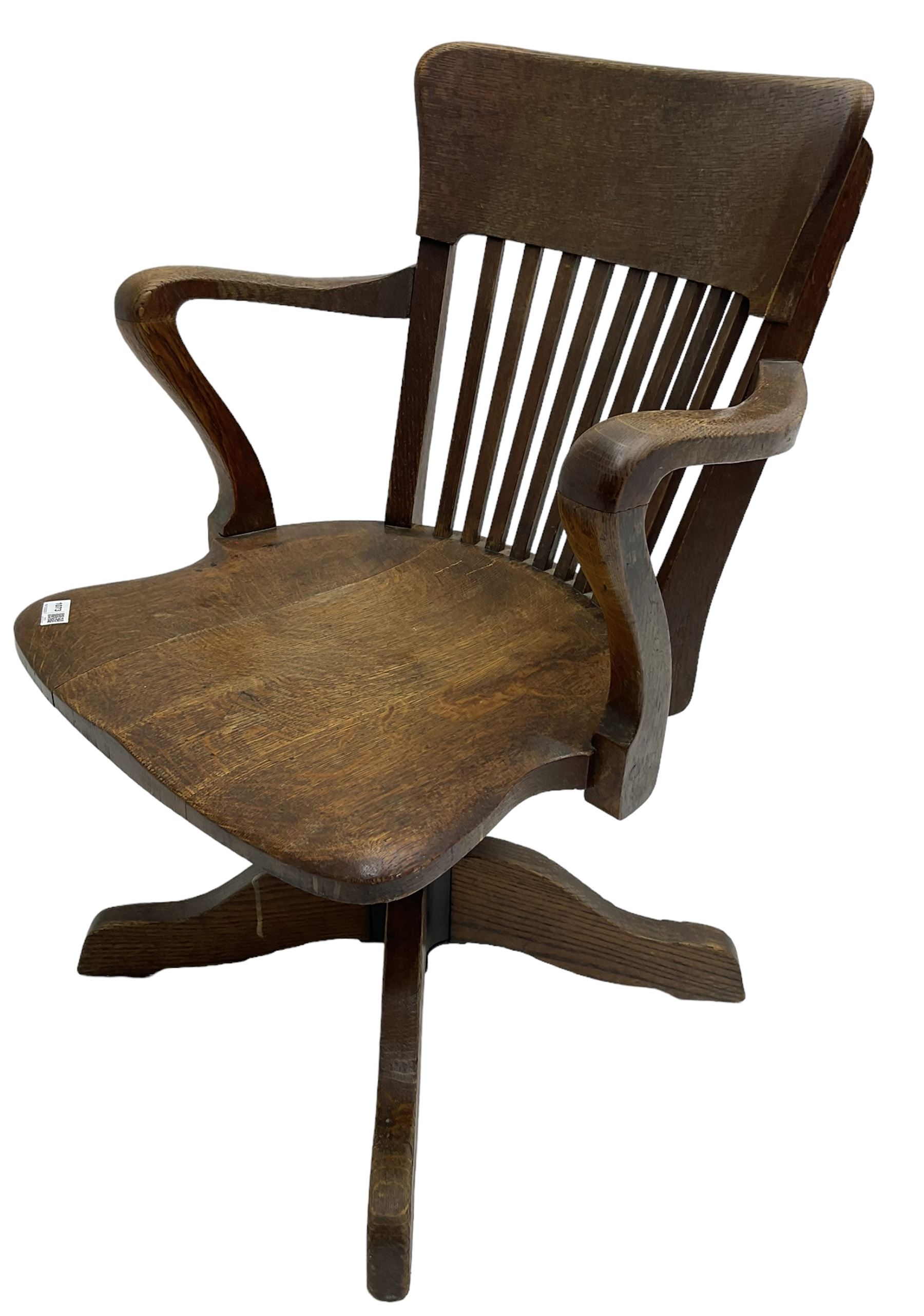Early 20th century swivel office desk chair, shaped bar back over vertical rails, dished seat, on four splayed supports