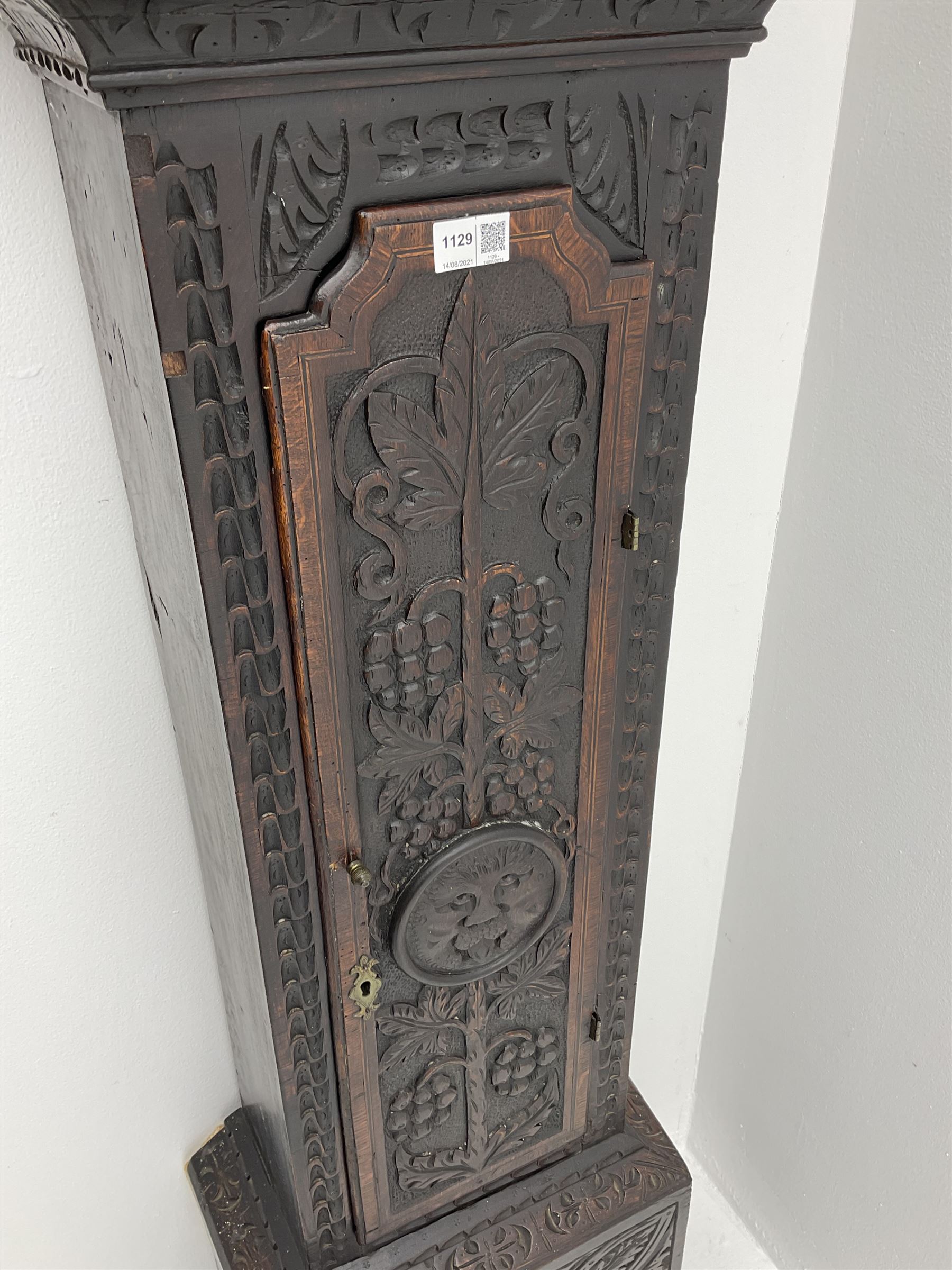 18th century oak longcase clock with later carving, the hood with projecting cornice over square glazed door, trunk door carved with tree of life, foliage carved base, on ogee bracket feet, brass dial with Roman chapter ring and subsidiary seconds and calendar aperture, ornate mask cast spandrels, twin train driven movement striking on bell 