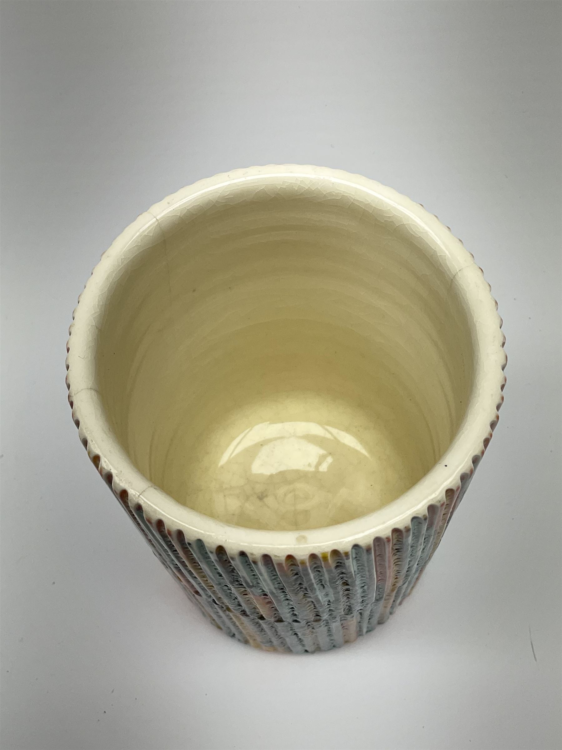 A Poole Pottery Delphis vase, shape 83, with textured effect in merging tones of red, yellow and blue, with printed mark beneath, H15cm.