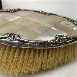 A silver and mother of pearl mounted hairbrush, hallmarked W J Myatt & Co, Birmingham 1909, two silver mounted clothes brushes and a comb mount, each with engine turned decoration, hallmarked Walker & Hall, Sheffield 1951/1952, a cased set of six silver handled knives in Kings pattern, hallmarked Sheffield 1959, maker's mark worn and indistinct, plus a mother of pearl handled cake knife, and three decanter labels, marked Brandy, Whisky, and Sherry. 