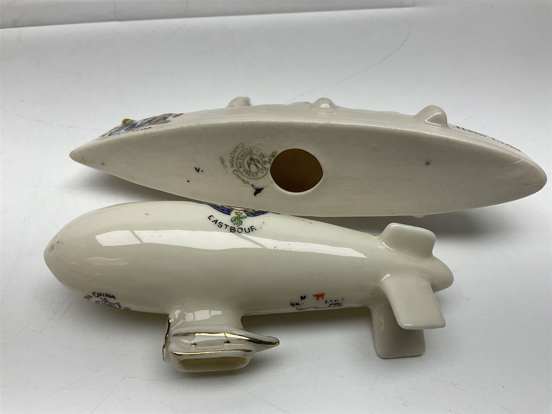 Ten WW1 crested china military models comprising submarine, four ships including Lusitania, four Zeppelins/balloons and an aircraft; various makers including Arcadian China, Swan China, Carlton China, Waterfall, Grafton China etc; various crests including Saint Neots, Great Yarmouth, Tewksbury, Swanage, Simons Town, Hull etc (10)