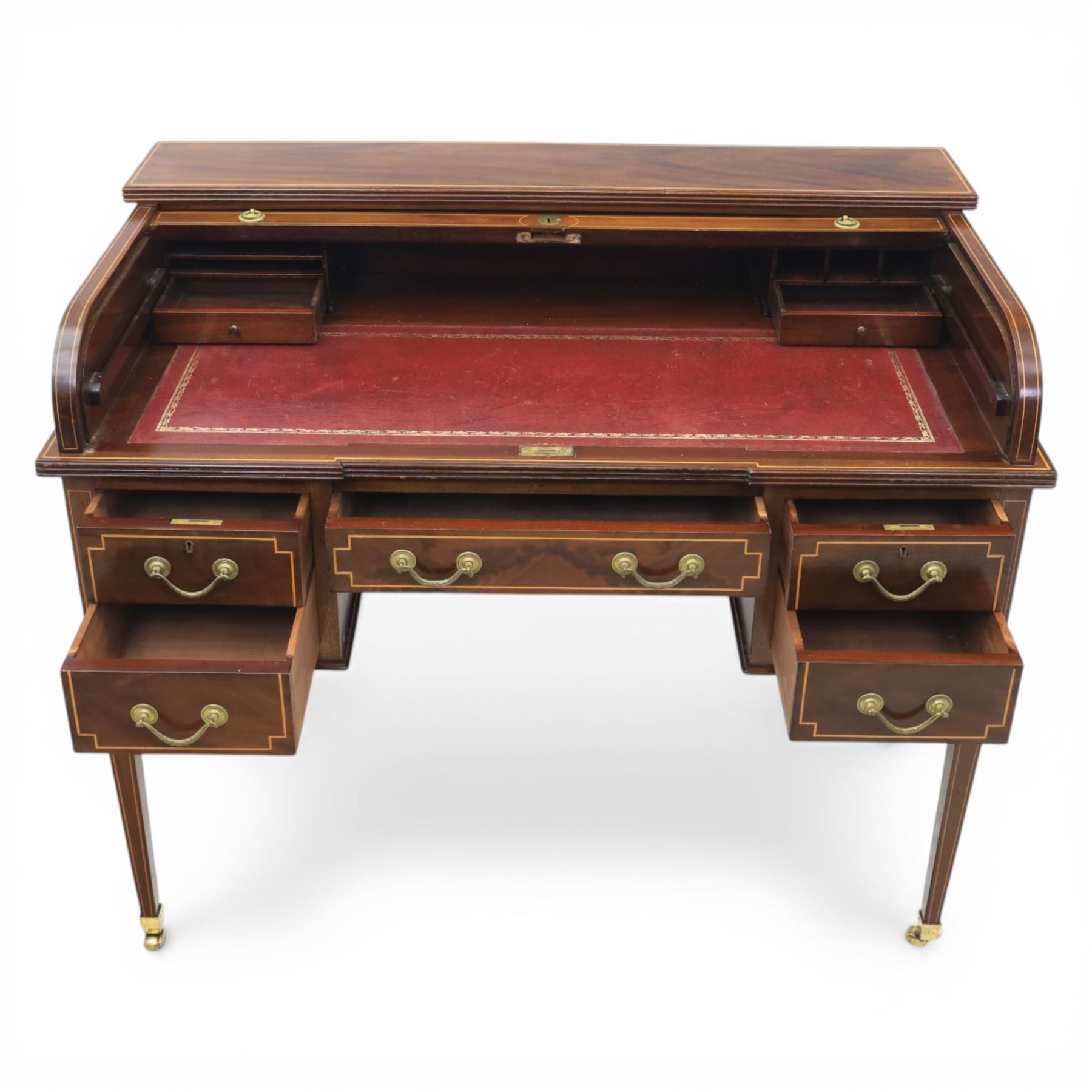 George III style inlaid mahogany tambour desk, the roll top enclosing fitted interior with small drawers and compartments above inset leather writing surface, over three frieze drawers, raised on square tapering supports with brass caps and castors