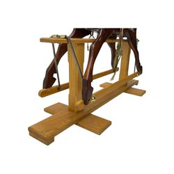 Contemporary carved wooden rocking horse, with leather saddle and bridle, horsehair mane and tail, raised on a pine stand with swing iron supports